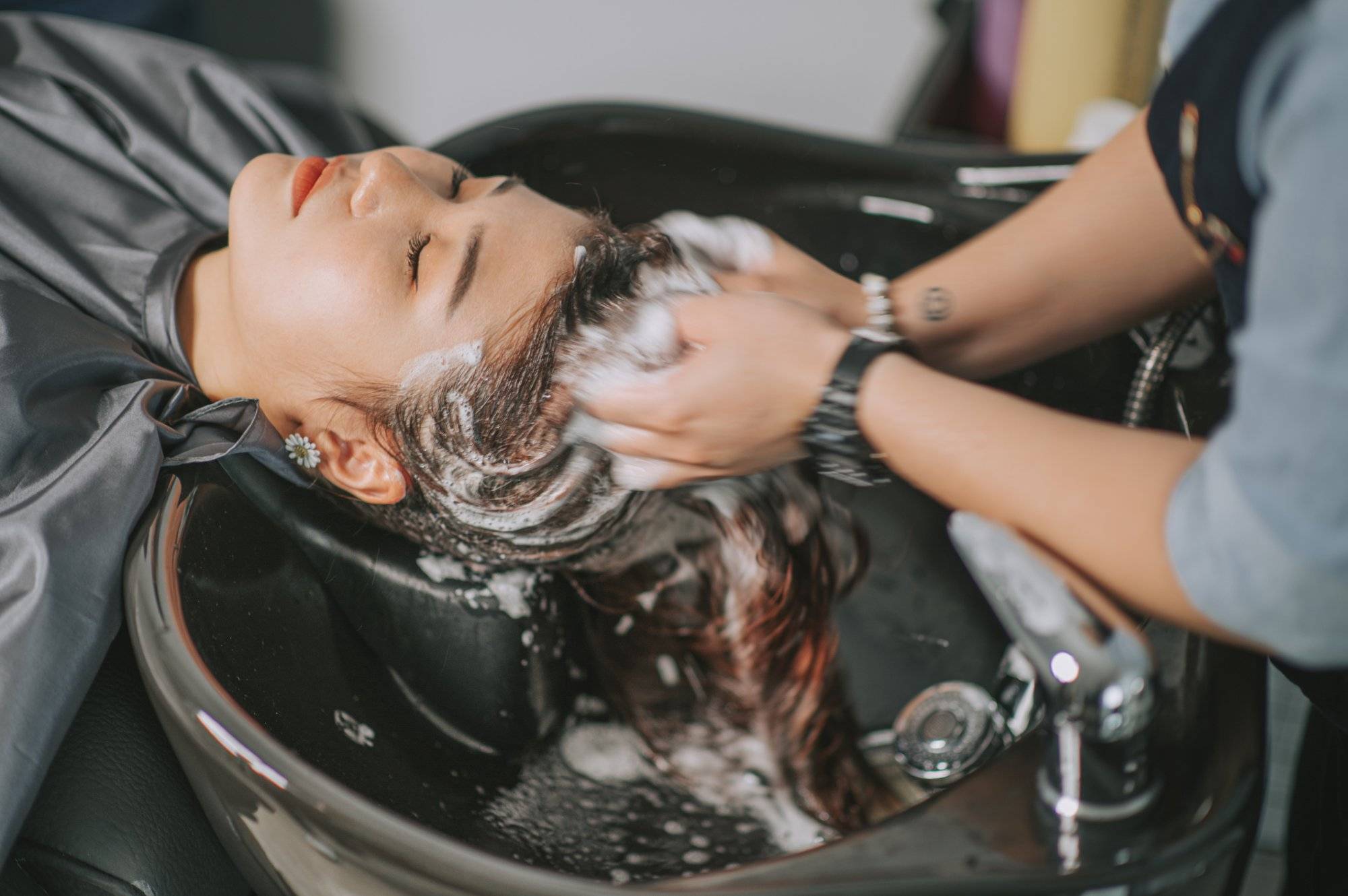 Directly above Asian chinese female lying down for hair wash at hair salon with eyes closed Directly above Asian chinese female lying down for hair wash at hair salon with eyes closed