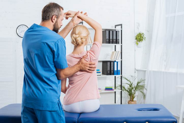 physiotherapist stretching patients arm on massage table in hospital